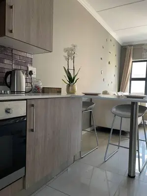 a kitchen with a counter and some chairs in it at 1 Bedroom Sleek, Spotless, Work-from-home Sanctuary in Midrand