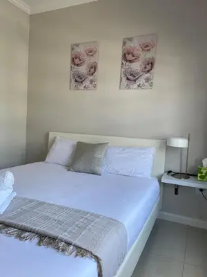 a bed in a bedroom with two pictures on the wall at 1 Bedroom Sleek, Spotless, Work-from-home Sanctuary in Midrand
