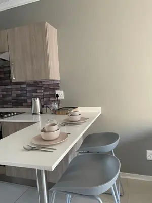 a kitchen with two chairs and a table with bowls on it at 1 Bedroom Sleek, Spotless, Work-from-home Sanctuary in Midrand