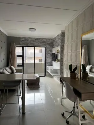 a living room with a dining table and a couch at 1 Bedroom Sleek, Spotless, Work-from-home Sanctuary in Midrand