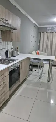 a kitchen with a table and some chairs in it at 1 Bedroom Sleek, Spotless, Work-from-home Sanctuary in Midrand