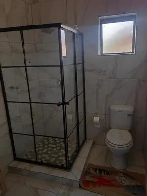 a bathroom with a shower with a toilet and a window at Choosers Express Boutique Hotel Room 4 in Centurion