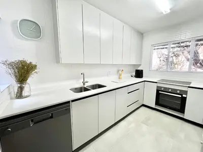a kitchen with white cabinets and a sink and a window at Thornhill Tranquility in Pretoria