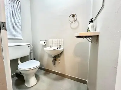 a white bathroom with a toilet and a sink at Thornhill Tranquility in Pretoria