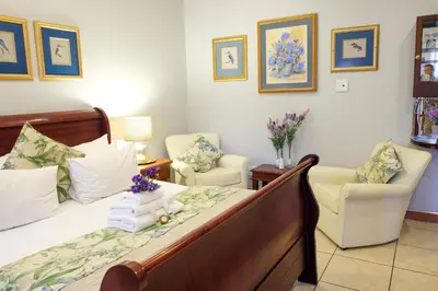 a bedroom with a bed and two chairs at Waterkloof Guest House in Pretoria