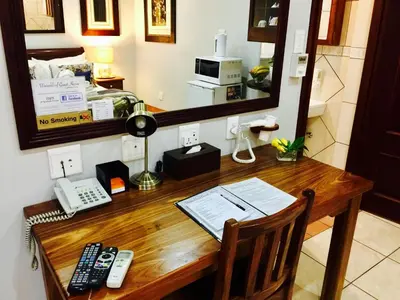 a wooden desk with a telephone and a mirror at Waterkloof Guest House in Pretoria