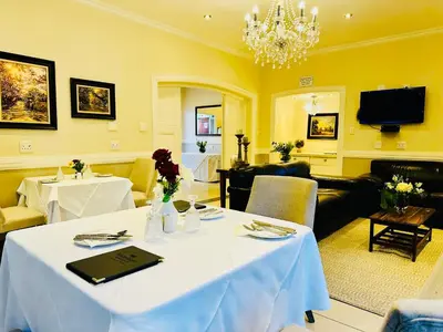 a dining room with two tables and a chandelier at Waterkloof Guest House in Pretoria
