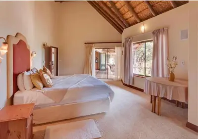 a bedroom with a large bed and a table at 205 Zebula 4 Bedroom with 2 bedroom Cottage in Mabula