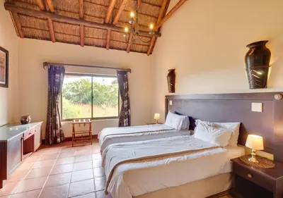 a bedroom with a large bed and a window at 205 Zebula 4 Bedroom with 2 bedroom Cottage in Mabula