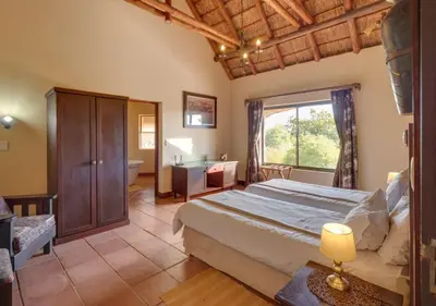 a bedroom with a large bed and a desk and a bed at 205 Zebula 4 Bedroom with 2 bedroom Cottage in Mabula