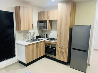 a kitchen with wooden cabinets and a stainless steel refrigerator at KT Nest in Midrand