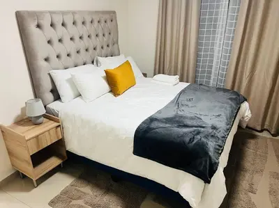 a bedroom with a large bed with a large headboard at KT Nest in Midrand