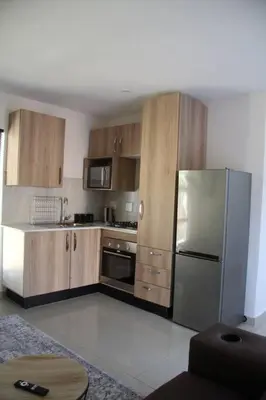 a kitchen with wooden cabinets and a stainless steel refrigerator at KT Nest in Midrand