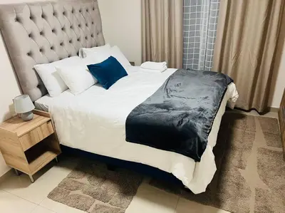 a bedroom with a large bed with blue pillows at KT Nest in Midrand