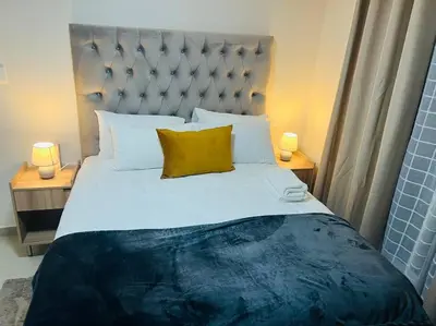 a bedroom with a large bed with two lamps at KT Nest in Midrand