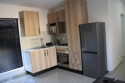 a kitchen with a black refrigerator and wooden cabinets at KT Nest in Midrand