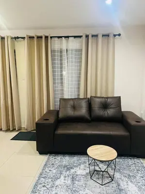 a living room with a black couch and a table at KT Nest in Midrand