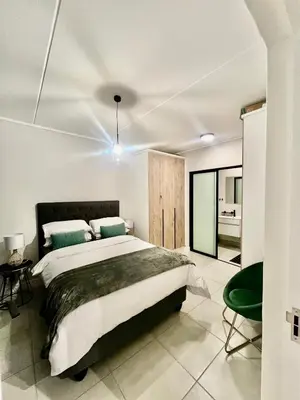 a bedroom with a large bed and a green chair at The Blyde Bliss in Pretoria