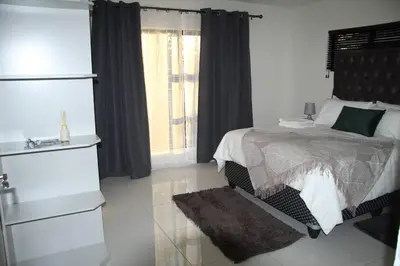 a white bedroom with a bed and a window at KT Space in Midrand