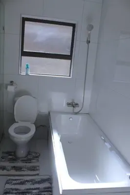 a bathroom with a tub and a toilet and a window at KT Space in Midrand