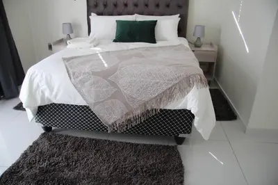 a bedroom with a large bed with a green pillow at KT Space in Midrand