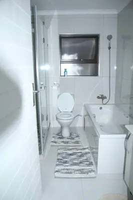 a white bathroom with a toilet and a sink at KT Space in Midrand