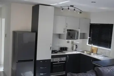 a kitchen with white cabinets and a black refrigerator at KT Space in Midrand
