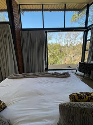 a large bed in a room with a large window at Modern Apartment on Letaba River in Tzaneen