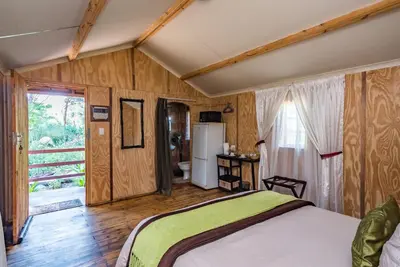 a bedroom with a bed and a bathroom with a window at Die Boskombuis en Gastehuis in Rayton