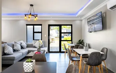 a living room with a couch and tables and chairs at Woman Era Guesthouse in Midrand
