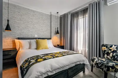 a bedroom with a bed and a chair at Woman Era Guesthouse in Midrand