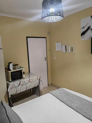 a bedroom with a bed and a door with a microwave at Choosers Express Boutique Hotel Room 3 in Centurion