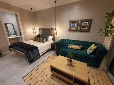 a living room with a bed and a green couch at Silver Views Guest Suite - No loadshedding! in Pretoria