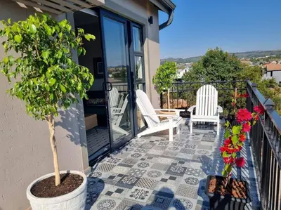a porch with a potted tree and two chairs on a balcony at Silver Views Guest Suite - No loadshedding! in Pretoria