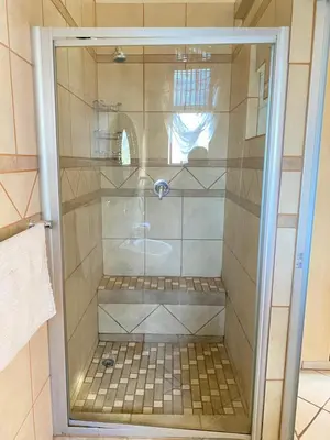 a shower with a glass door in a bathroom at Texas Phalaborwa guesthouse in Phalaborwa