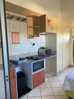 a kitchen with wooden cabinets and a stove top oven at Texas Phalaborwa guesthouse in Phalaborwa