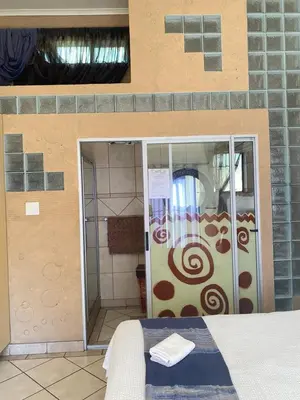 a shower with a glass door in a room at Texas Phalaborwa guesthouse in Phalaborwa