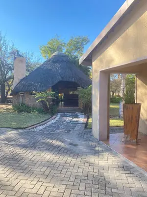 a building with a thatched roof and a brick walkway at Texas Phalaborwa guesthouse in Phalaborwa