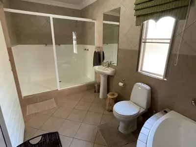 a bathroom with a toilet and a shower and a sink at Zomoya Game Farm in Vaalwater