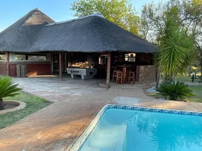 a house with a thatched roof and a swimming pool at Zomoya Game Farm in Vaalwater