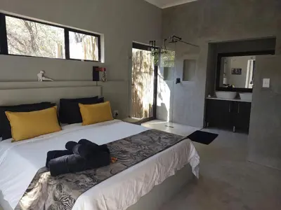 a bedroom with a large bed with yellow and blue pillows at House Motswiri in Marloth Park
