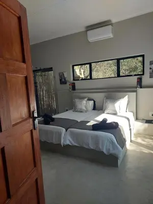 a bedroom with two beds and two windows at House Motswiri in Marloth Park