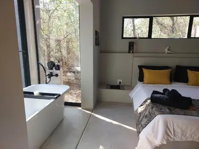 a bedroom with a bed and a sink and a window at House Motswiri in Marloth Park