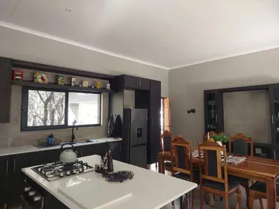 a kitchen and dining room with a stove and a table at House Motswiri in Marloth Park