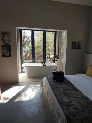 a bedroom with a bed and a tub and a window at House Motswiri in Marloth Park