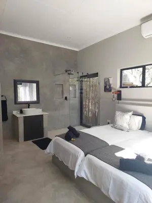 a bedroom with a large bed and a sink at House Motswiri in Marloth Park