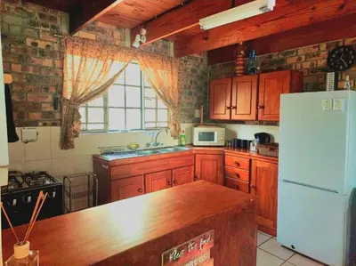 a kitchen with wooden cabinets and a white refrigerator at Ton & Trees in Marloth Park