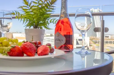 a table with a plate of fruit and a bottle of wine at Modern Luxury Apartment, Ellipse in Midrand
