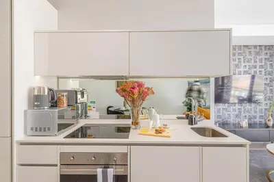a white kitchen with a sink and a microwave at Modern Luxury Apartment, Ellipse in Midrand