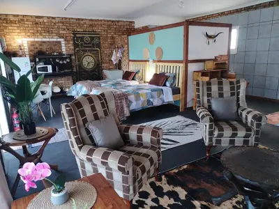 a bedroom with a bed and two chairs at 2K City Studios Not Self catering in Graskop